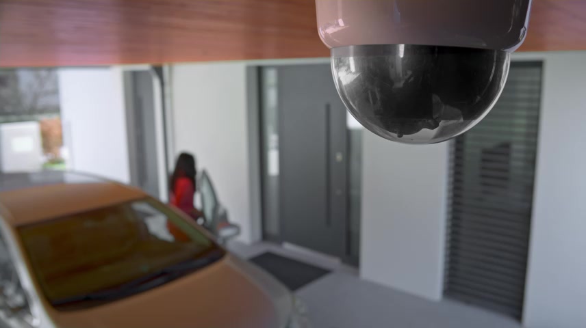 摄像机在车道上，一名女子将车停在家中.