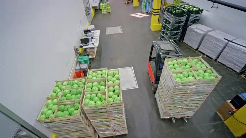 叉车将新鲜农产品从仓库走廊运出.