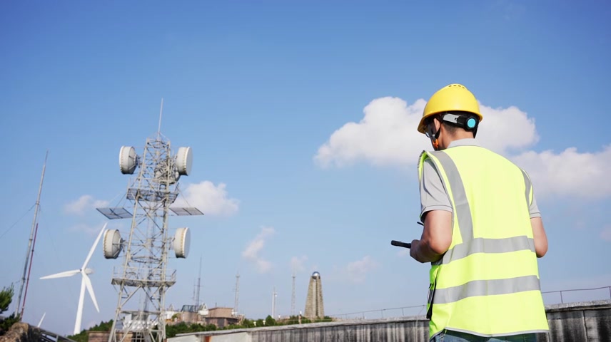 工程师在通信基站铁塔下平板电脑工作