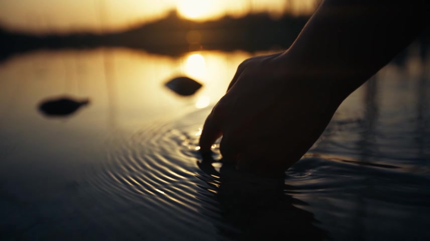 黄昏逆光湖面特写手划过水面意境空镜头视频