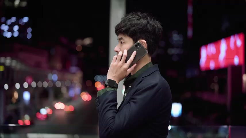 年轻的亚洲男子在夜间街头使用智能手机.