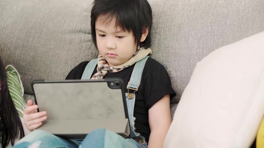 一群在教室里使用平板电脑的孩子，多民族的年轻男孩和女孩在小学里快乐地使用技术学习和玩游戏孩子们使用.